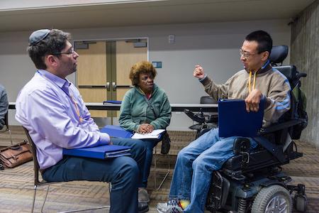 Three people deep in dialogue, one geturing with his hand.