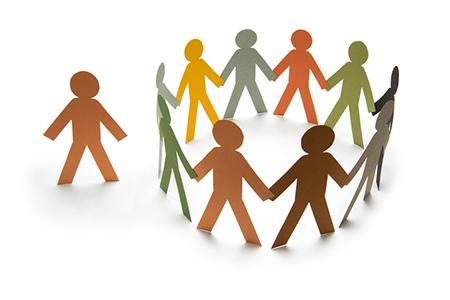 a circle of paper people of different colors holding hands with one unattached paper person on the outside of the circle.